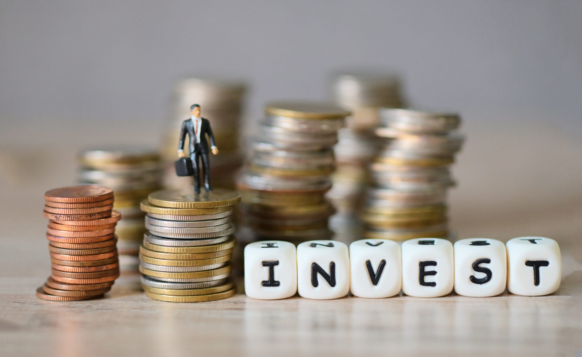 invest message and business man standing on a coin on wooden tab